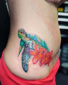 a woman's stomach with a turtle and flower tattoo on the side of her belly