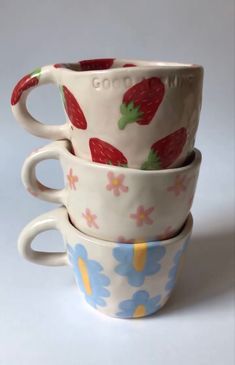 three cups stacked on top of each other with strawberries and flowers painted on them