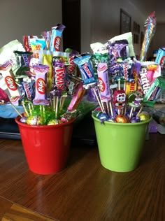 two buckets filled with candy sitting on top of a wooden table next to each other