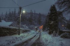 a snow covered road at night with street lights