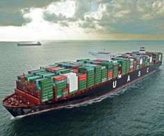 a large cargo ship with many containers on it's side in the ocean under a cloudy sky