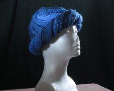 a white mannequin head wearing a blue knitted hat on top of a table