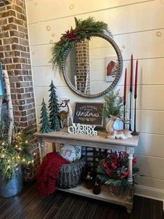 a table with christmas decorations on it in front of a brick wall and round mirror