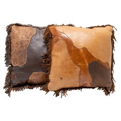 two brown and tan leather pillows with fringes on each pillow, one in the shape of a cow's head