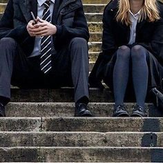 two people sitting on some steps with one holding a cell phone and the other looking at something