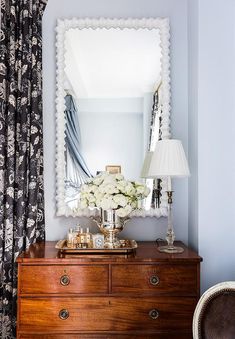 a dresser with flowers on top and a mirror above it