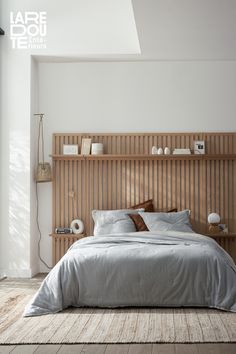 a large bed sitting next to a tall wooden headboard in a room with white walls