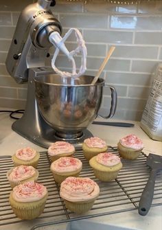 some cupcakes are on a rack near a mixer