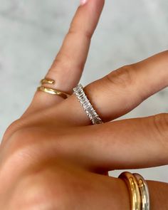 a woman's hand with two gold rings on it and one white ring in the middle