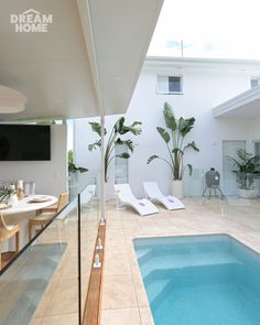 an indoor swimming pool with lounge chairs and television on the wall, next to it