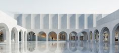 an empty building with arches and columns on the sides, reflecting water in the floor