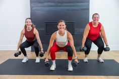 three women are doing squats with dumbbells