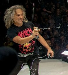 a man standing on top of a stage holding a microphone in front of an audience