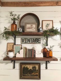 the shelves are filled with books and vases on top of each other in front of a white painted wall