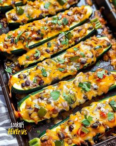 several stuffed zucchini boats are lined up on a baking sheet and ready to be eaten