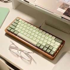 a computer keyboard sitting on top of a desk next to a pair of eyeglasses