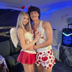 a man standing next to a woman in front of a couch with hearts on it