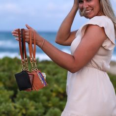 a woman in a white dress holding two purses on her shoulder and looking at the camera