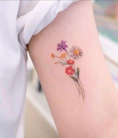 a close up of a person's arm with flowers tattooed on the left side