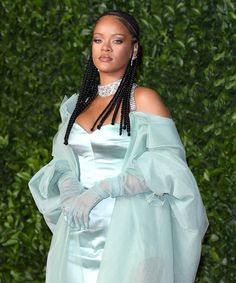 a woman with long braids wearing a light blue dress and matching gloves is standing in front of a green wall