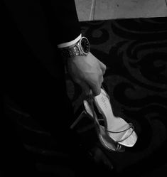 a man in a suit and tie holding onto his high heeled shoes