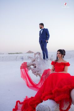 a woman in a red dress sitting next to a man in a blue suit