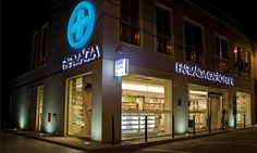 an illuminated store front at night with its lights on and the building lit up in blue