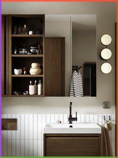 a bathroom sink sitting under a mirror next to a wooden cabinet