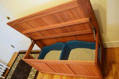 an open wooden box with two blue bins in it on top of a hard wood floor