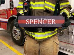 a firefighter holding a sign that says spencer on it's chest and standing in front of a fire truck