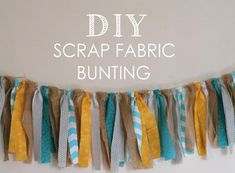 the diy scrap fabric bunting banner is hanging from a white wall with blue and yellow strips on it