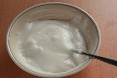 a bowl of yogurt with a spoon in it sitting on a table top