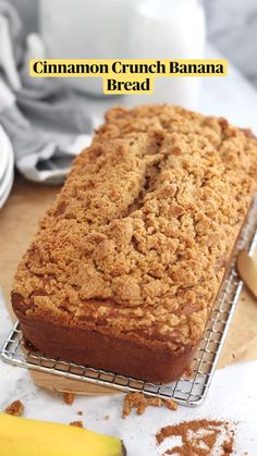 a loaf of cinnamon crumb banana bread on a cooling rack next to some bananas