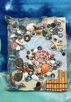 an art work made out of shells and other items on a blue background with the ocean theme