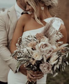 a bride and groom standing together with their bouquet