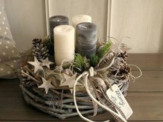 some candles are sitting in a basket with pine cones