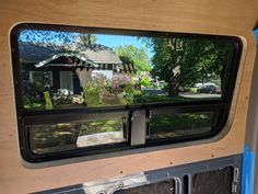 the rear view mirror of a vehicle with trees and houses in the back ground behind it