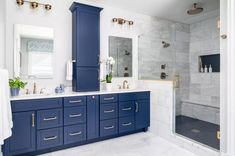 a large bathroom with blue cabinets and marble counter tops, along with gold accents on the fixtures