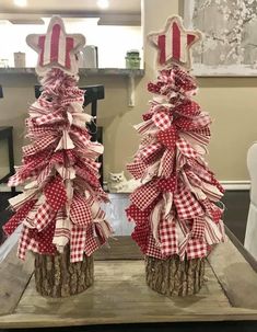 two red and white christmas trees sitting on top of a wooden table