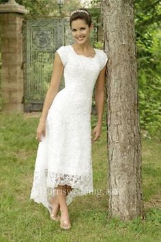 a woman standing next to a tree wearing a white dress