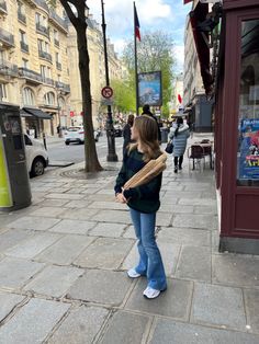 a woman standing on the sidewalk with a baseball bat in her hand