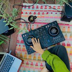 a person sitting at a table with a laptop and dj's equipment on it