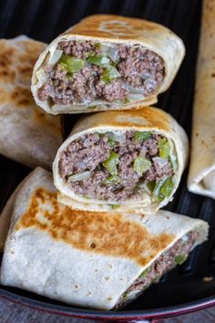 three burritos sitting on top of a grill