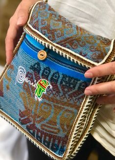 a woman is holding a colorful purse in her hands