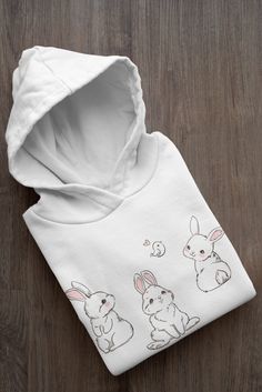 Bunny hoodie, rabbit sweatshirt, rabbit hoodie, easter bunny sweatshirt, bunny mom Hoodie A classic hoodie with a large front pouch pocket and drawstrings in matching color.Preshrunk fleece knitAir jet yarn gives softer feel and reduced pillingDouble-lined hood with color-matched drawcordTear away labelDouble-needle stitching at shoulder, armhole, neck, waistband and cuffsPouch pocket1 x 1 rib with spandexQuarter-turned to eliminate centre creaseFibre content varies by color, see color list for White Hoodie With Cartoon Print For Spring, Cute White Hoodie With Drawstring Hood, Cute Hoodie Sweatshirt With Kangaroo Pocket, Rabbit Hoodie, Bunny Sweater, Bunny Sweatshirt, Bunny Hoodie, Bunny Mom, Tshirt Knot