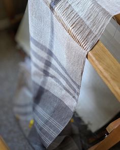 a plaid table cloth on a wooden chair with a white and gray blanket draped over it