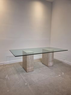 a glass table sitting in the middle of a room with white walls and flooring