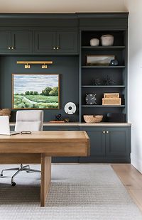 a home office with built - in bookcases and an art piece on the wall