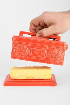 a hand is holding an orange plastic radio and toaster on a red platter