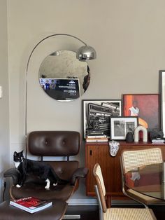 a black and white cat sitting on top of a chair in a living room next to a table